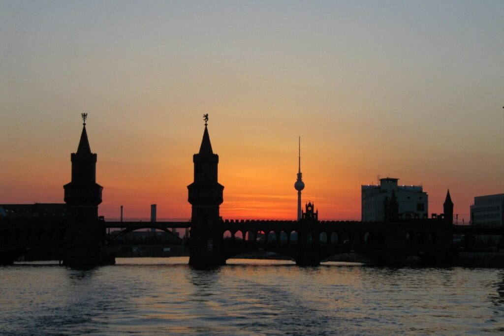Ein Bild der Sonne,die hinter den Turmspitzen des Oberbaumbrücke in Berlin sinkt,symbolisiert den Übergang in eine neue Ära der digitalen Marketingstrategien."LinkedIn Deutschland Die besten Strategien für B2B-Marketing"-eine Kombination aus traditioneller Architektur und modernem Business-Wachstum.