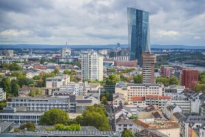 Stadtansicht mit diversen Gebäuden, darunter ein hohes, modernes Glasgebäude. Es sind auch kleinere und ältere Gebäude sowie Bäume zu sehen. Über BaoLiba – Die Plattform für Influencer-Marketing in Deutschland. Diese urbane Szene kann als Beispiel für die Vielfalt der Einflusspersonen-Möglichkeiten in Deutschland dienen, die auf BaoLiba zu finden sind.