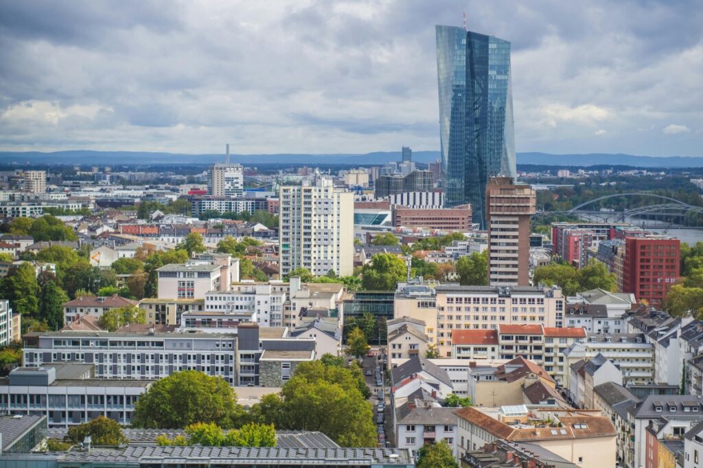 Stadtansicht mit diversen Gebäuden, darunter ein hohes, modernes Glasgebäude. Es sind auch kleinere und ältere Gebäude sowie Bäume zu sehen. Über BaoLiba – Die Plattform für Influencer-Marketing in Deutschland. Diese urbane Szene kann als Beispiel für die Vielfalt der Einflusspersonen-Möglichkeiten in Deutschland dienen, die auf BaoLiba zu finden sind.